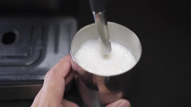 咖啡师用慢动作蒸牛奶。蒸汽棒加热牛奶。错误溅起牛奶。工作失败洒了牛奶。视频素材
