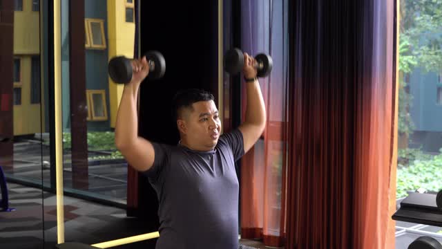 超重男子在健身房用哑铃锻炼视频下载