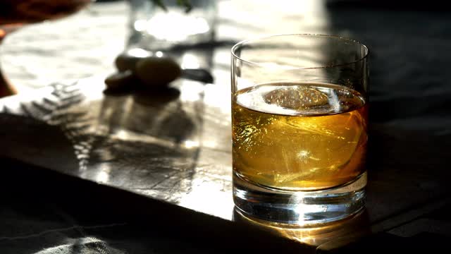 经典禁酒令曼哈顿鸡尾酒在老式岩石玻璃，与球体冰块，被搅拌。视频下载