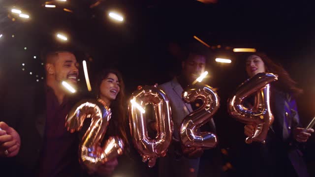一群朋友拿着2024年的气球和烟花庆祝新年视频购买