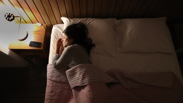 女人晚上在床上辗转反侧，焦虑不安。正在关夜灯的人视频素材