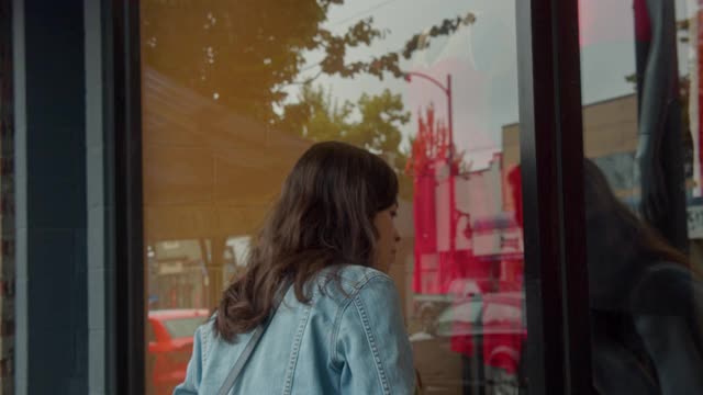 年轻女子在服装店外橱窗购物视频下载
