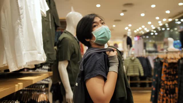 在服装店购物的亚洲女性戴着面具视频素材