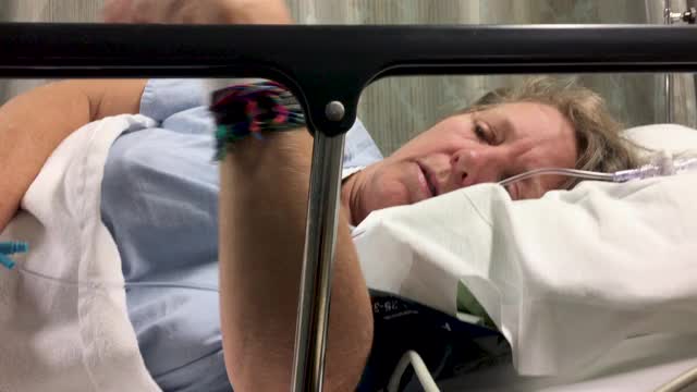一个低角度的妇女躺在医院的床上，连接着静脉输液视频下载