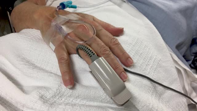 一个女人的手接受静脉输液和连接到脉搏血氧计的特写视频素材