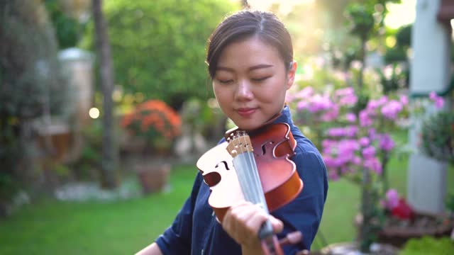 年轻的亚洲女子在户外拉小提琴视频下载