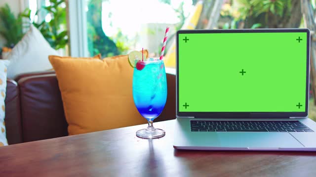 绿色屏幕的笔记本电脑坐在一个咖啡店的桌子上视频下载