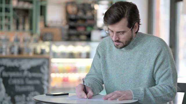 年轻人在咖啡馆的纸上写字视频素材