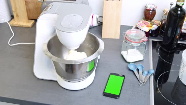 DS智能手机与色度键绿色屏幕旁边的一个立式搅拌机在厨房视频下载