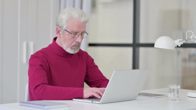 在办公室用笔记本电脑工作的老人视频下载