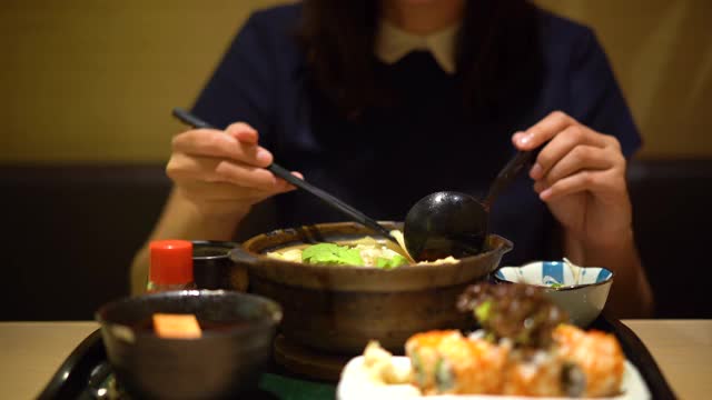 年轻的亚洲女子正在吃一碗日本乌冬视频素材