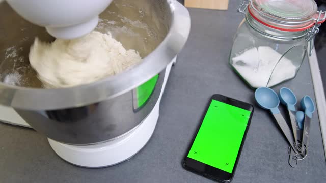 DS智能手机与色度键绿色屏幕旁边的一个立式搅拌机在厨房视频下载
