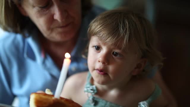 祖母吹蜡烛和婴儿孙子蹒跚学步庆祝生日视频素材