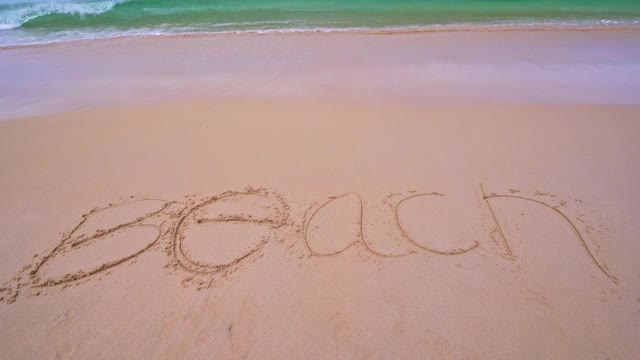 海浪擦去海滩文字在白色的沙滩上写在早晨热带的海滩美丽的白色沙滩和海浪在沙滩上撞击视频下载