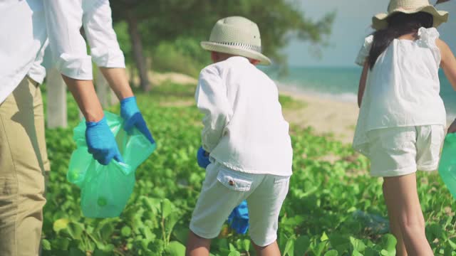 父亲，母亲，儿子和女儿一起清理海滩。视频下载