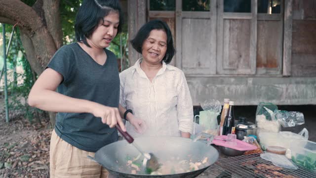 亚洲妈妈和女儿在家里烹饪传统食物视频素材