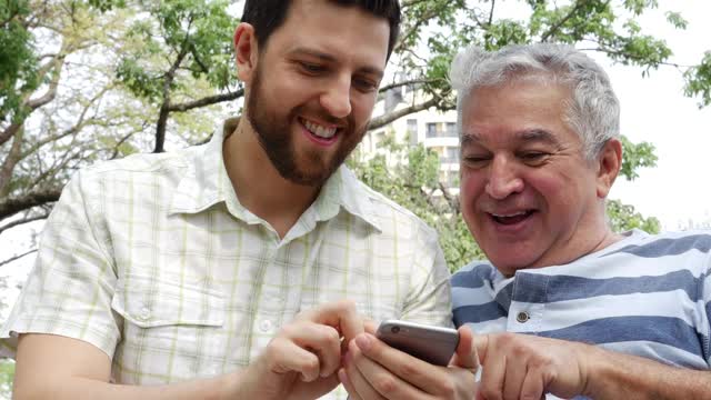 爸爸和儿子在公园里用智能手机视频素材