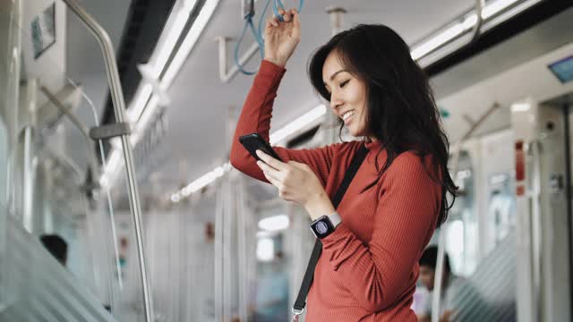年轻漂亮的女人在公共交通工具上使用智能手机视频素材