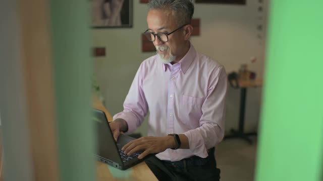 留着胡子的亚洲华裔大四学生在咖啡馆用笔记本电脑工作视频下载