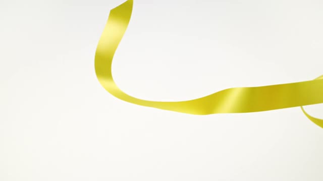 白色背景上的黄色丝带，用于庆祝活动和新年派对，生日派对，圣诞节或任何节日，在超级慢镜头和特写中摇摆和卷曲视频下载