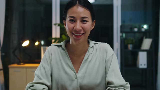 肖像美丽的行政女商务智能休闲装看着相机和微笑，快乐在现代办公室工作的夜晚。视频素材