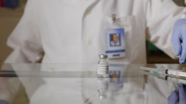 医生、卫生保健工作者或医疗技术人员按照制造商的指示稀释covid - 19疫苗，轻轻摇晃小瓶，为免疫接种过程做好准备。视频素材