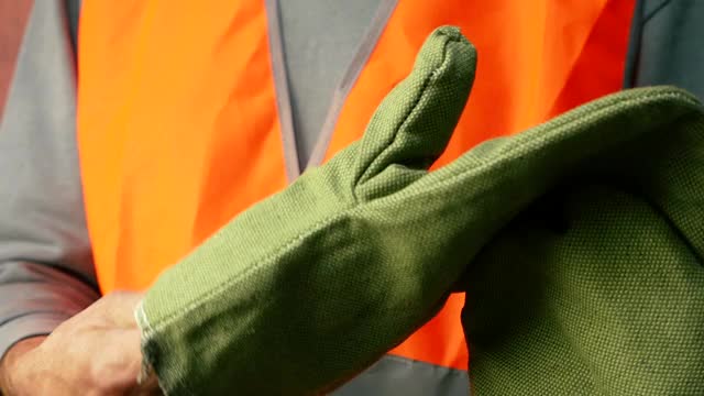 一名身穿工作服、身穿橙色反光背心的男子手上戴着工作手套。一个穿工作服的建筑工。戴着防护手套的工人开始工作。有选择性的重点视频下载