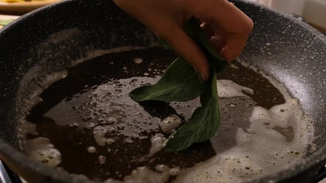 慢动作把鼠尾草和黄油放在煎锅里视频素材