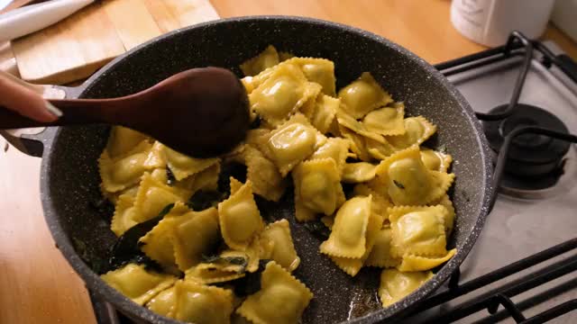 慢动作，用黄油和鼠尾草在煎锅中搅拌和烹饪饺子面视频素材