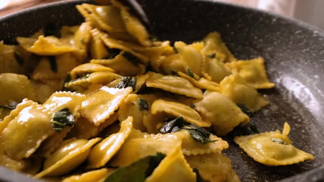 用黄油和鼠尾草在煎锅中搅拌和烹饪饺子意面视频素材