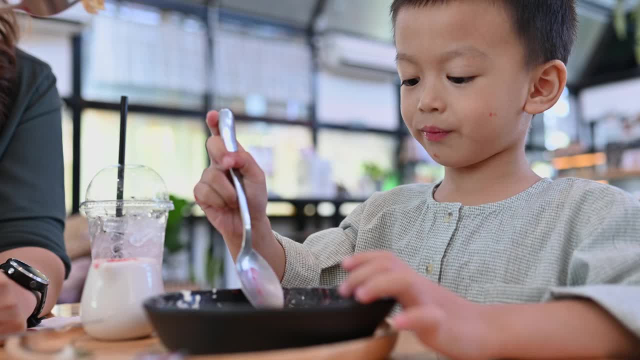 亚洲男孩在咖啡馆里吃着美味的糖果视频下载