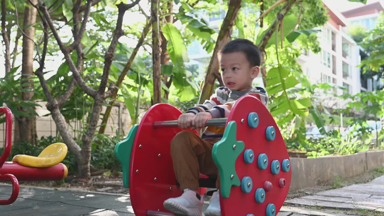 可爱的亚洲男孩在操场上玩得很开心视频下载