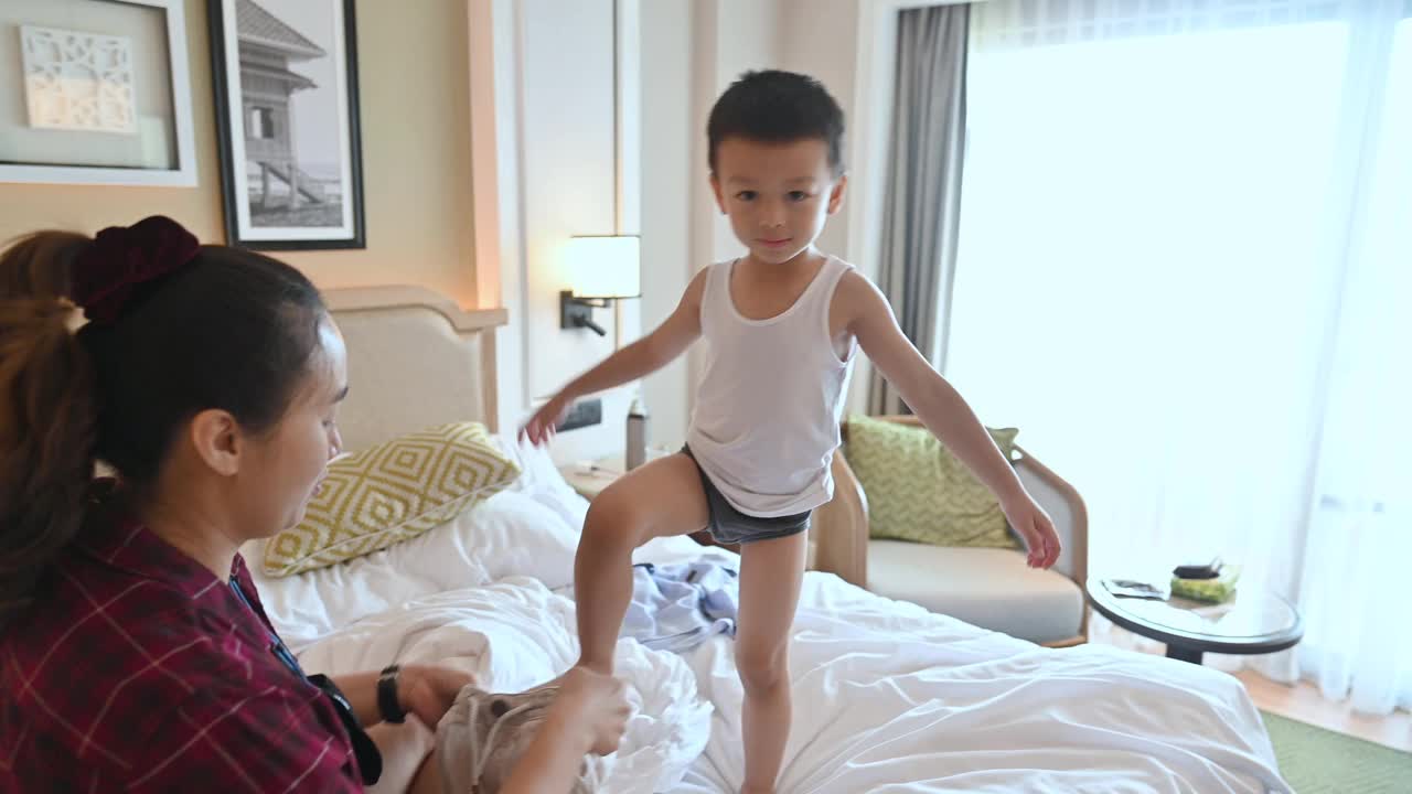 亚洲妈妈为儿子穿衣在酒店房间的床上视频下载
