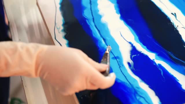 在绘画中作线漆。戴着手套的手拿着抹刀和向导刷油漆。视频下载