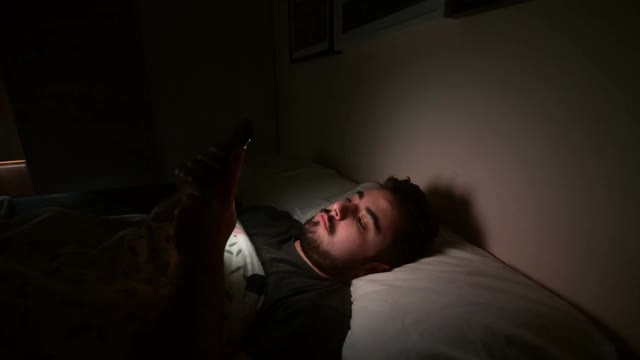 年轻人在床上玩智能手机视频下载