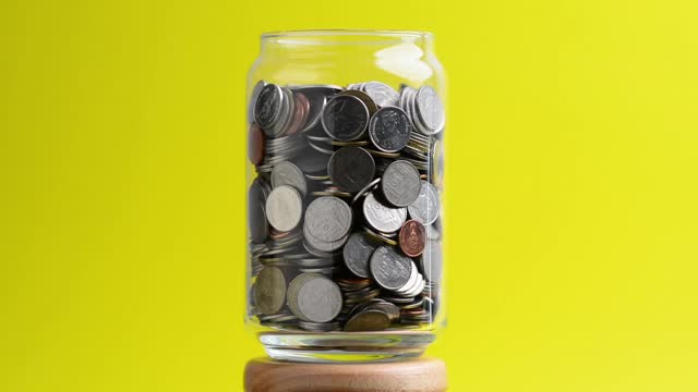 透明玻璃瓶里的硬币在旋转。转钱的概念视频下载