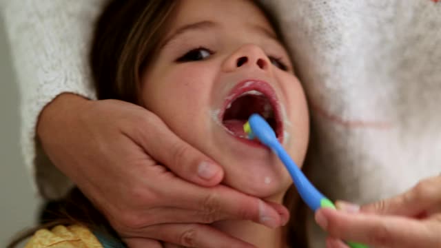 妈妈在给孩子刷牙。父母用牙刷刷子牙视频素材