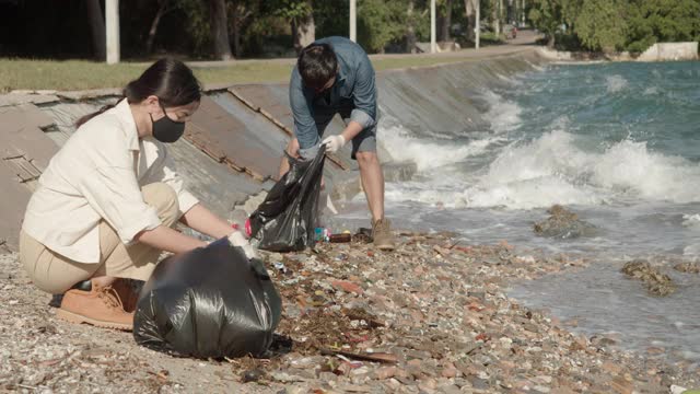 海洋垃圾，两个清洁海滩的志愿者。通过收集海滩上的垃圾。视频素材