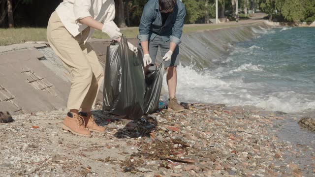 海洋垃圾，两个清洁海滩的志愿者。通过收集海滩上的垃圾。视频素材