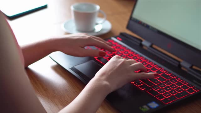一个在笔记本电脑公司工作的年轻女性，用笔记本电脑键盘打字视频素材