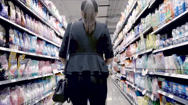 美丽的商务女性戴着防护口罩在超市购物。视频素材