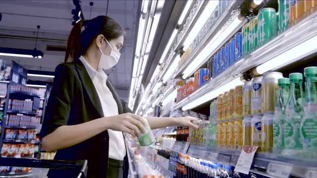 美丽的商务女性戴着防护口罩在超市购物。视频素材