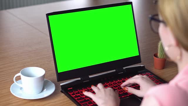 电子教育，女性在笔记本电脑上观看以绿色屏幕为色键技术，笔记本电脑绿色模拟屏幕。女孩在网上学习电脑视频素材