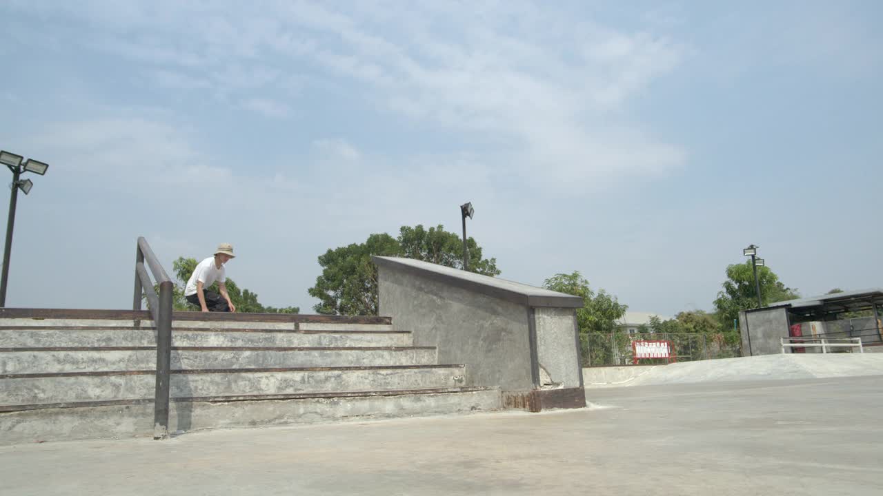 慢动作拍摄的年轻亚洲男子滑板跳跃在滑板公园白天的时间视频下载