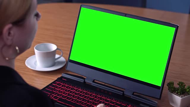电子教育，女性在笔记本电脑上观看以绿色屏幕为色键技术，笔记本电脑绿色模拟屏幕。女孩在网上学习电脑视频素材