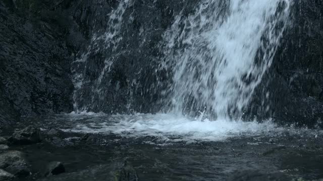 瀑布从岩石深渊倾泻而下。水溅到岩石上。大量的水从石头上倾泻而下，流进小溪视频素材