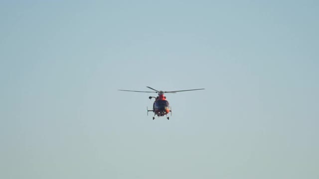 一架橙色的直升机在海上沿着海岸警卫队飞行。——慢动作视频下载