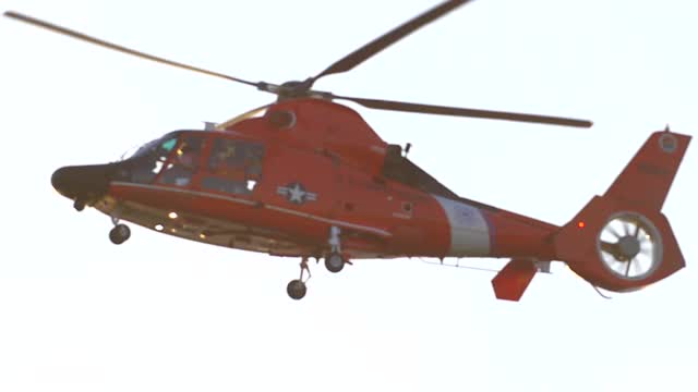 一架橙色的直升机在海上沿着海岸警卫队飞行。——慢动作视频素材