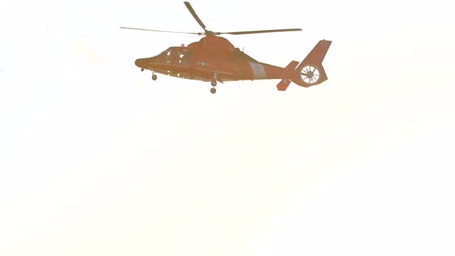 一架橙色的直升机在海上沿着海岸警卫队飞行。——慢动作视频素材