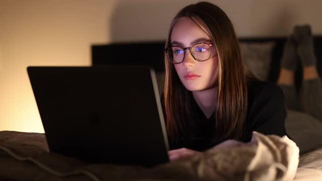 严肃的少女在床上用笔记本电脑读坏消息视频下载